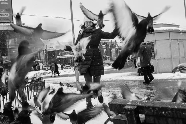 Репортажная фотография - девушка разгоняет голубей